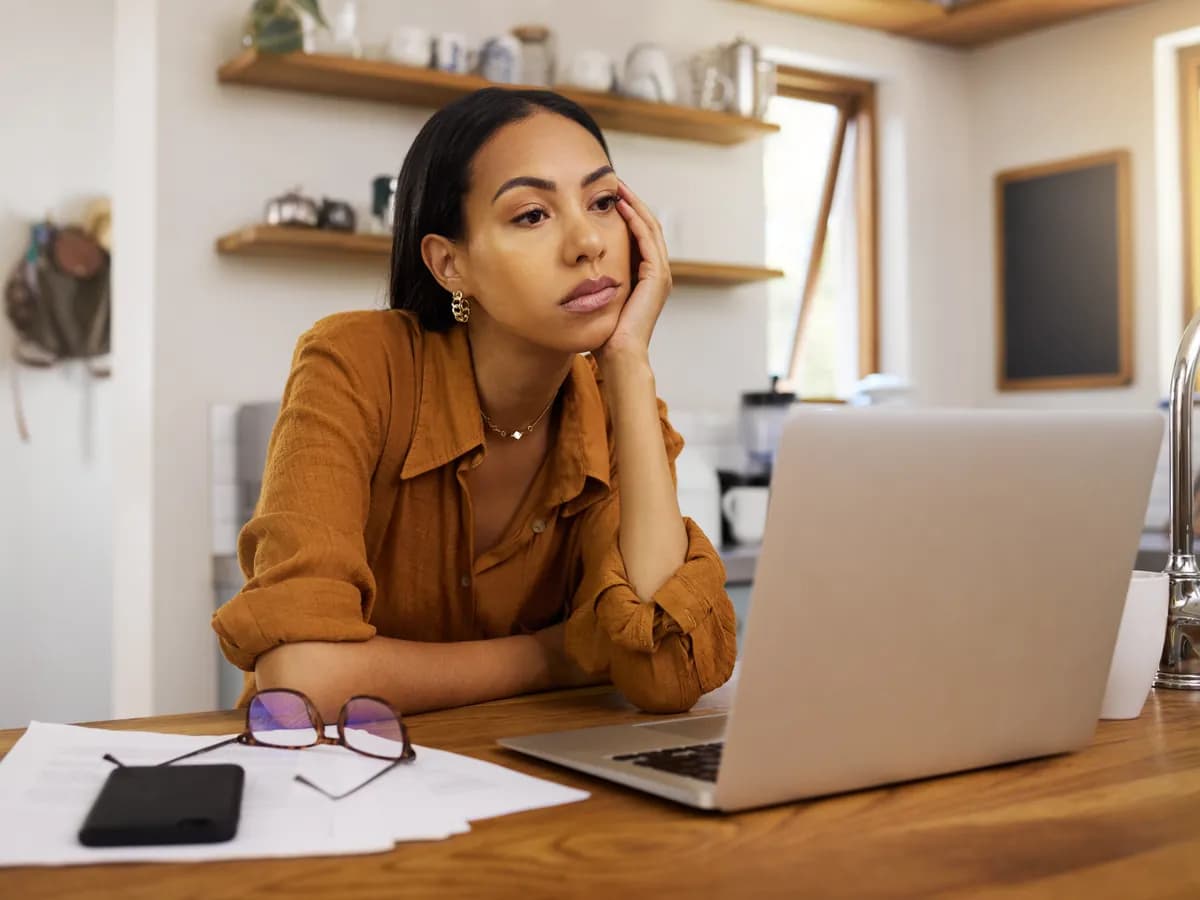 Tired woman at her laptop, struggling with brain fog and exhaustion