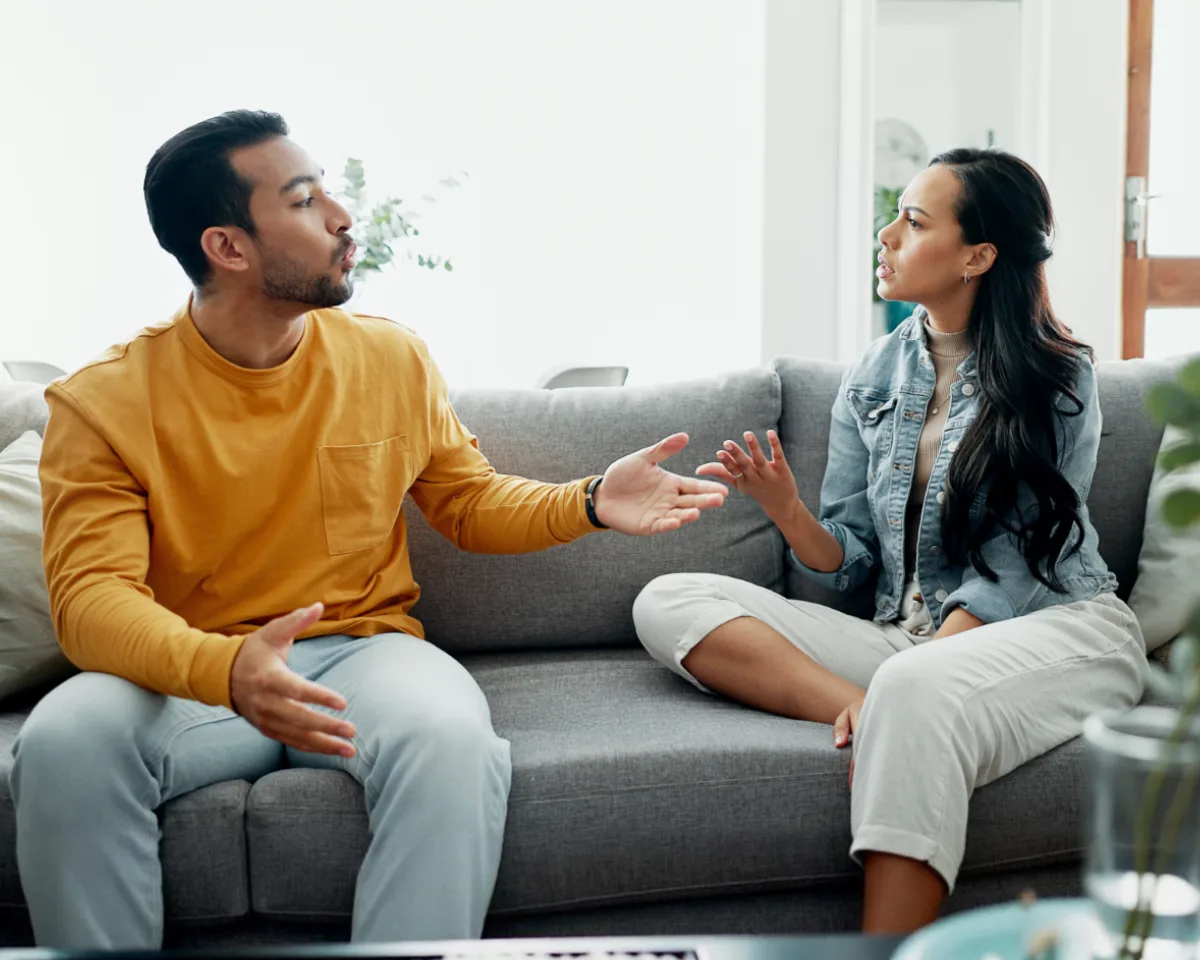 Couple sitting apart on a sofa, frustrated and disconnected during an argument