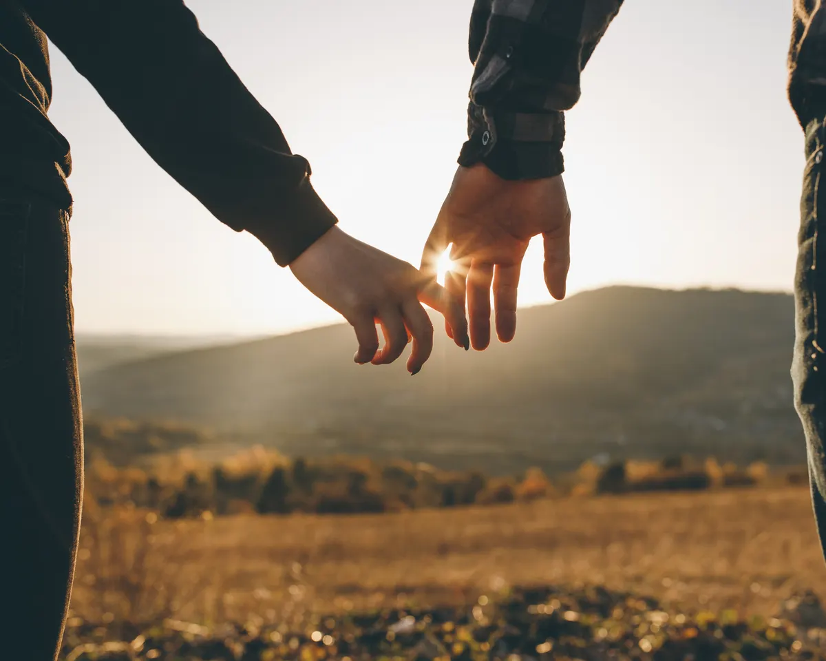 Close-up of two partners' hands joining together, lit by a soft sunlight flare