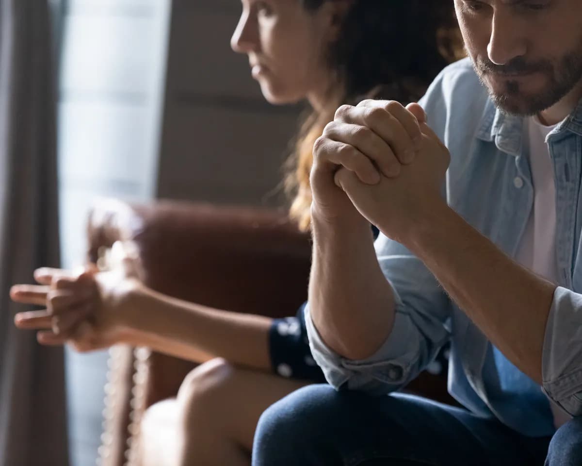Couple sitting apart on a sofa, distant after a breach of trust
