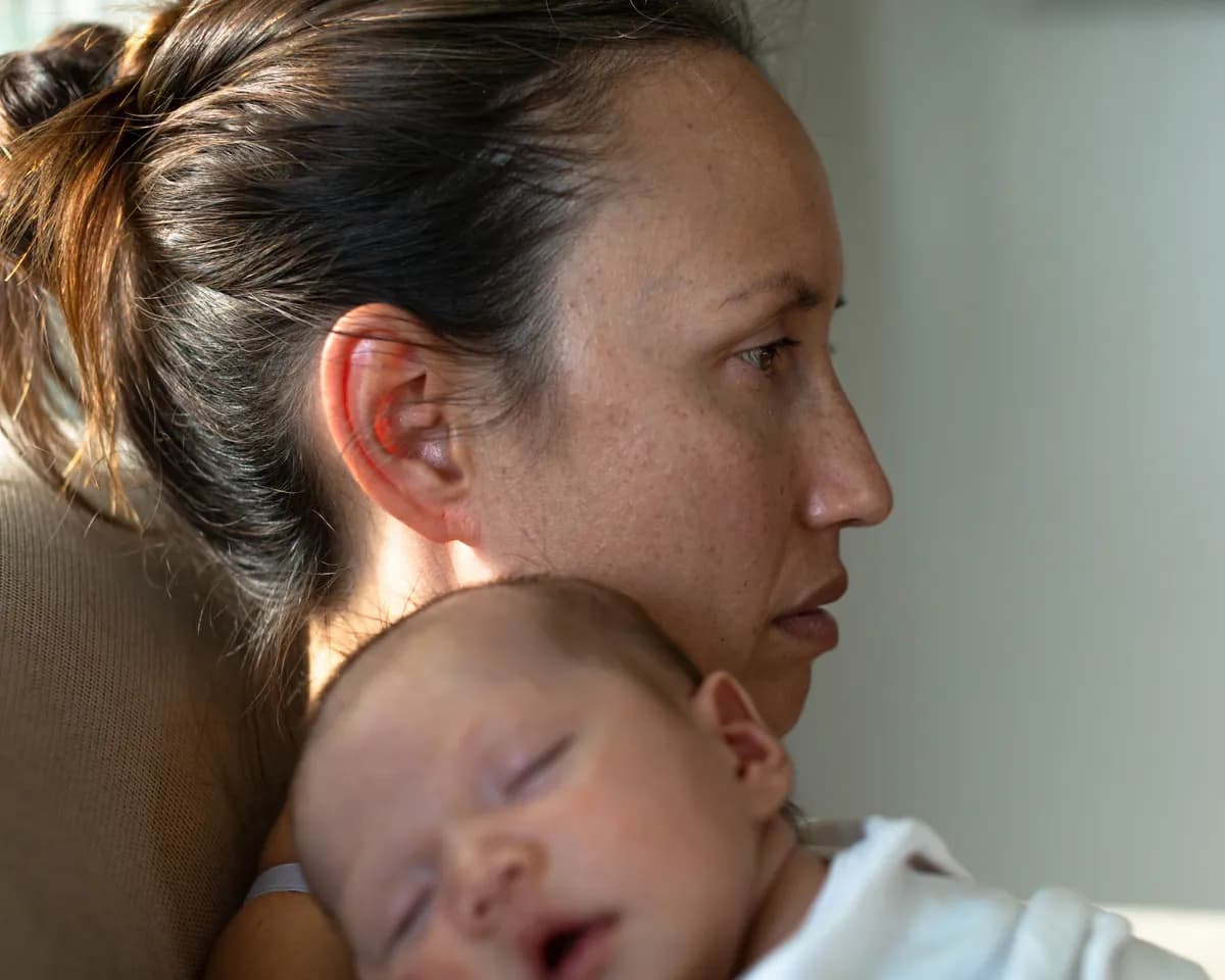 Woman sitting alone at home, reflecting on a difficult birth experience