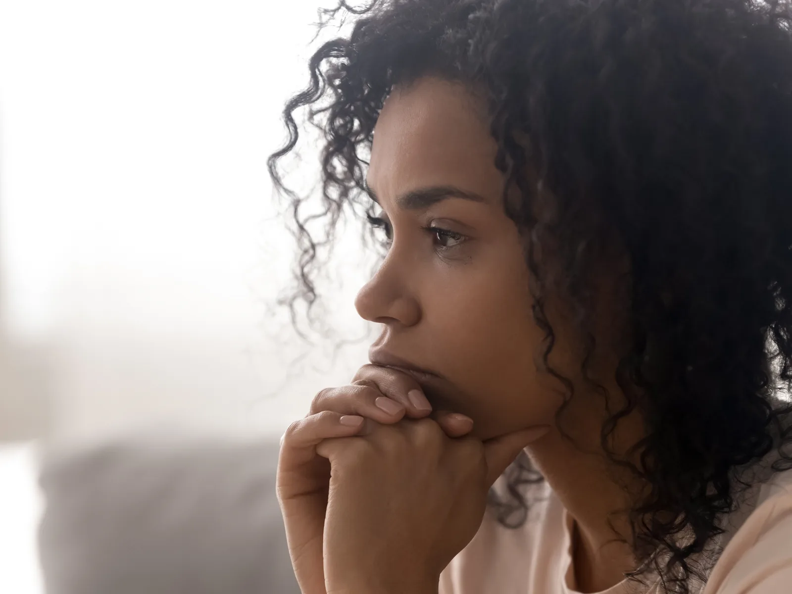 Woman resting her chin on her hand, lost in anxious thought