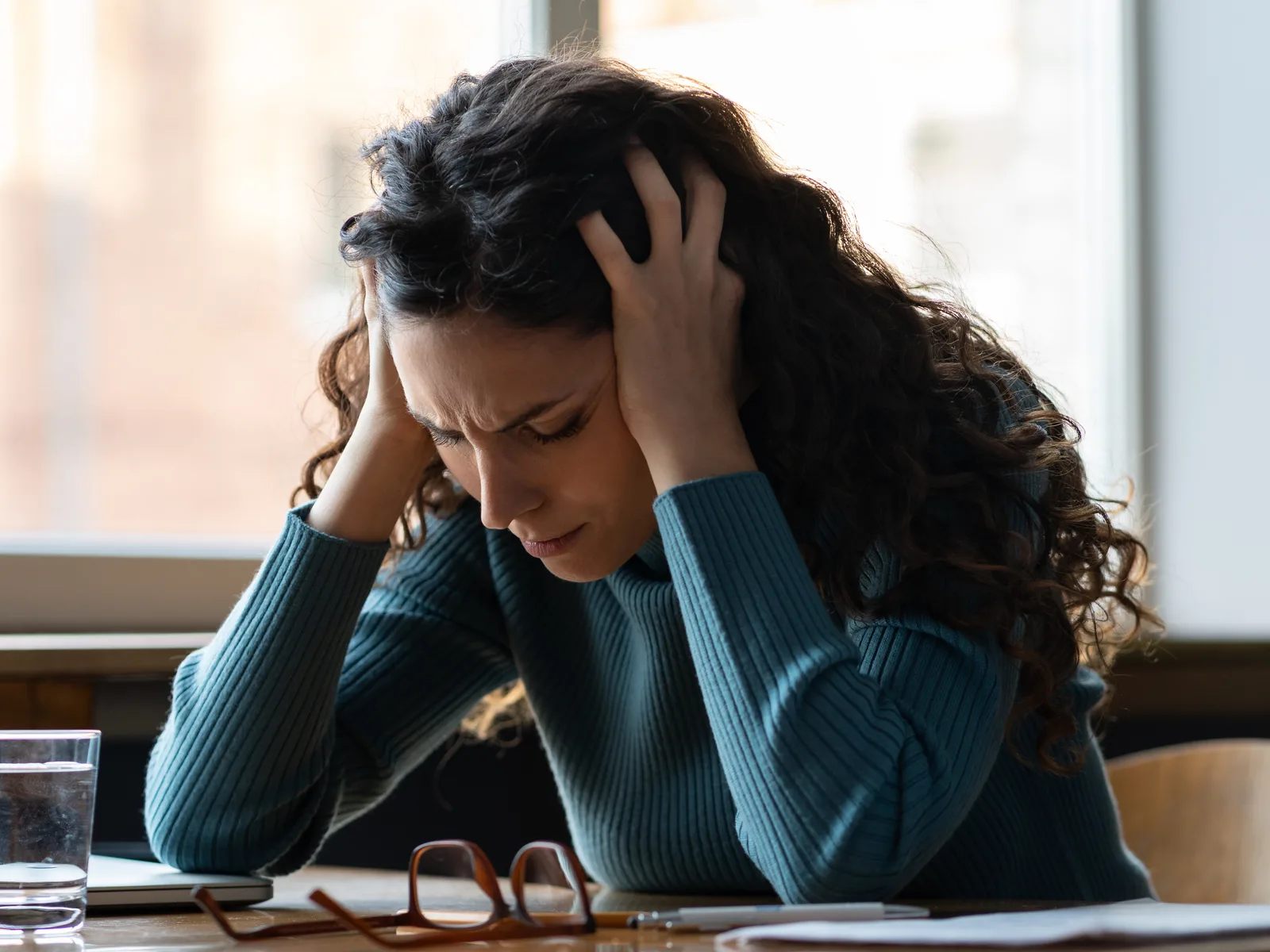 Exhausted woman at her desk, resting her head in her hand