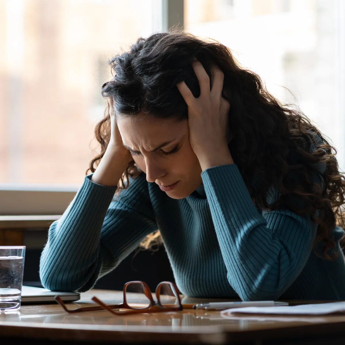 Woman curled on a couch, reflecting the weight of burnout