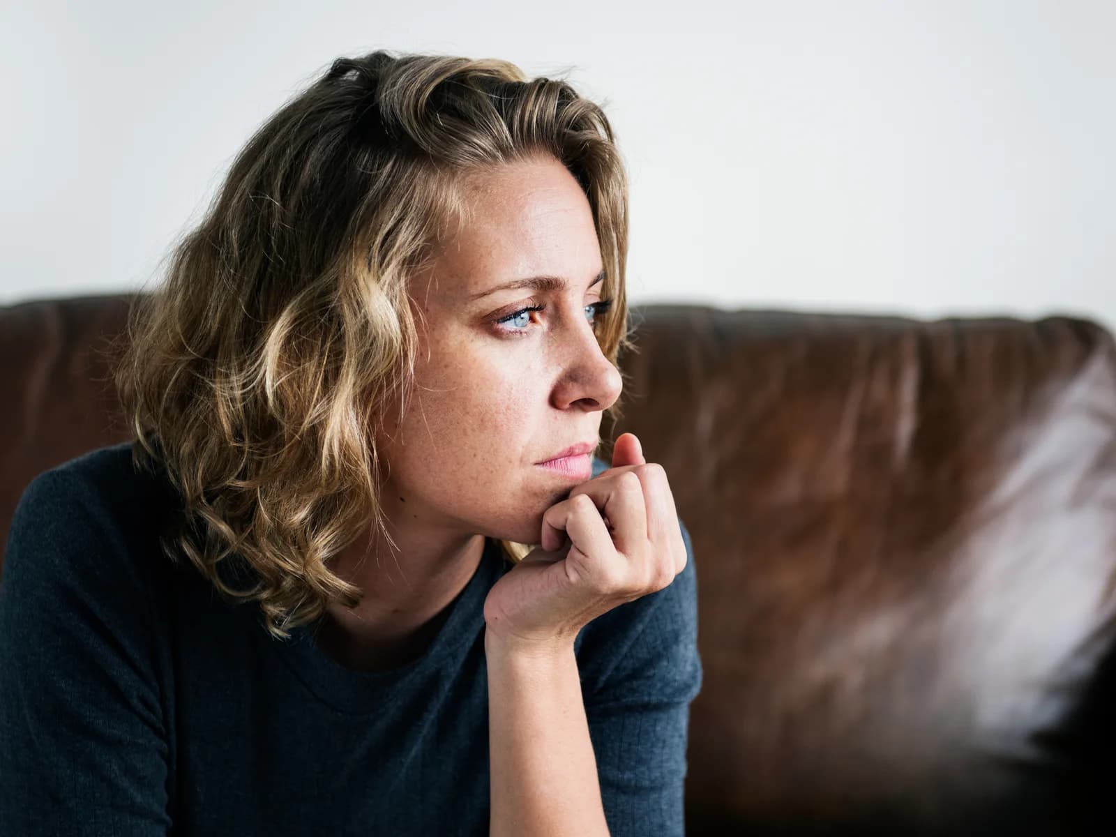 Woman sitting on a sofa, looking downcast and reflective
