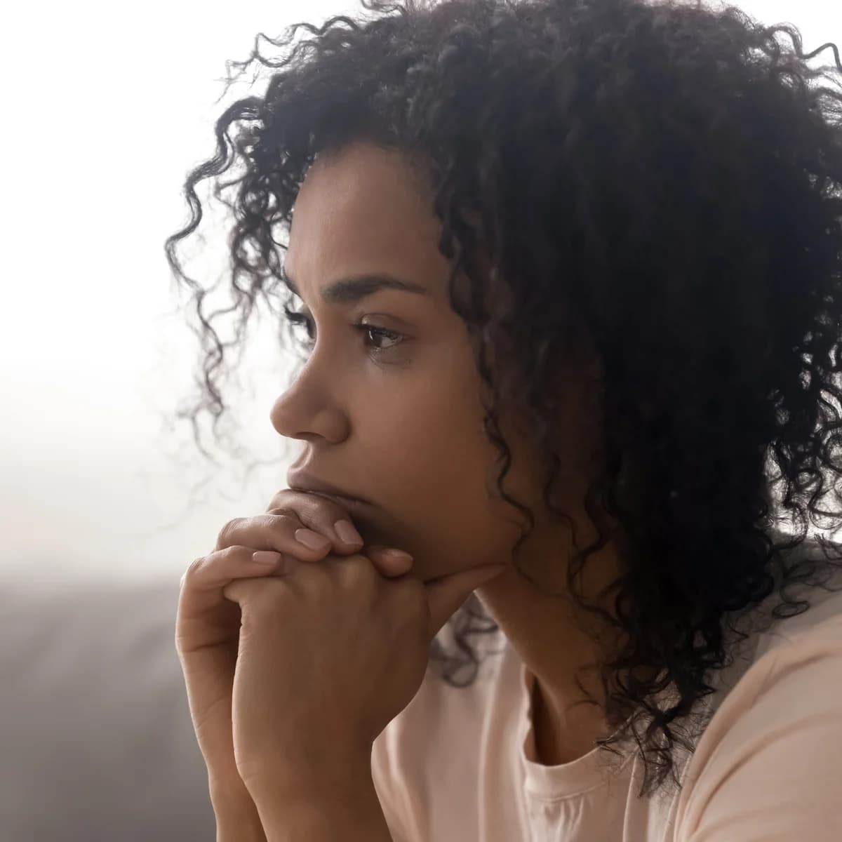 Pensive woman in close reflection, sitting with a quiet ache