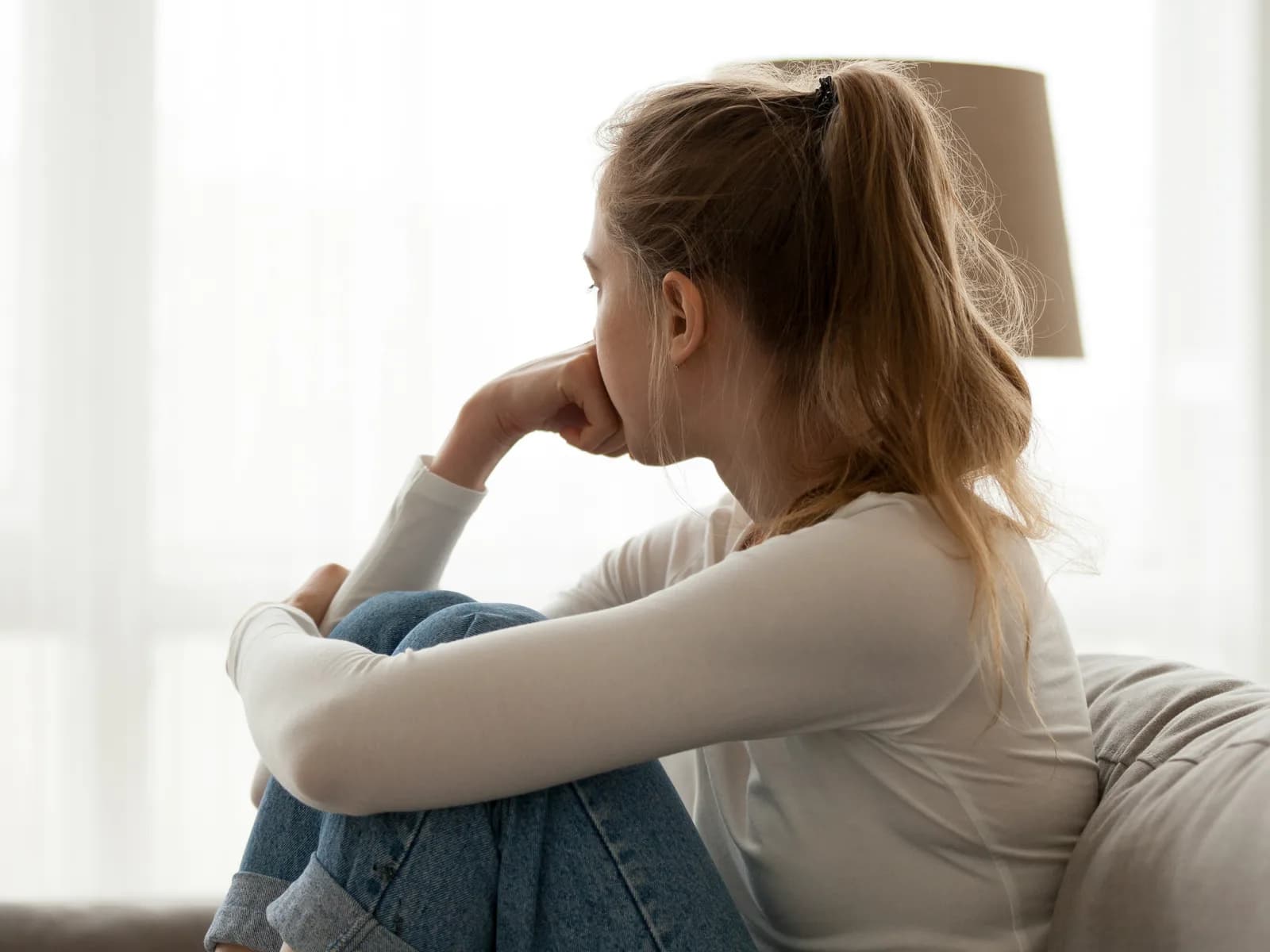 Young woman gazing out a window, contemplating a life change