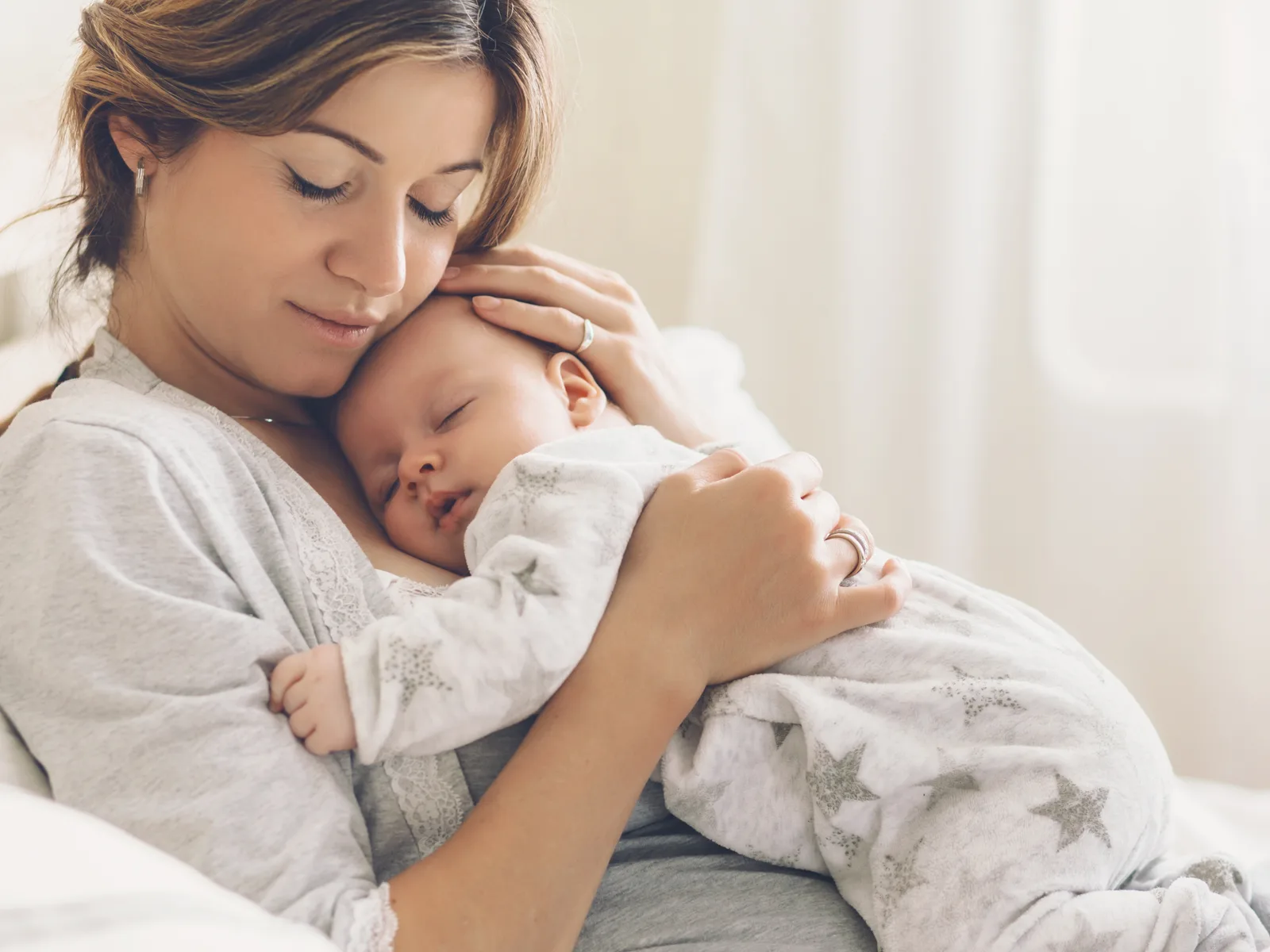 Mother tenderly cradling her sleeping newborn