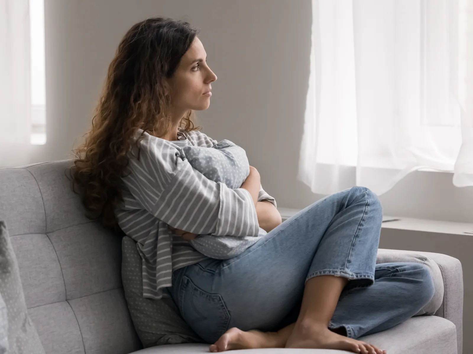 Woman sitting on a couch, withdrawn and lost in thought