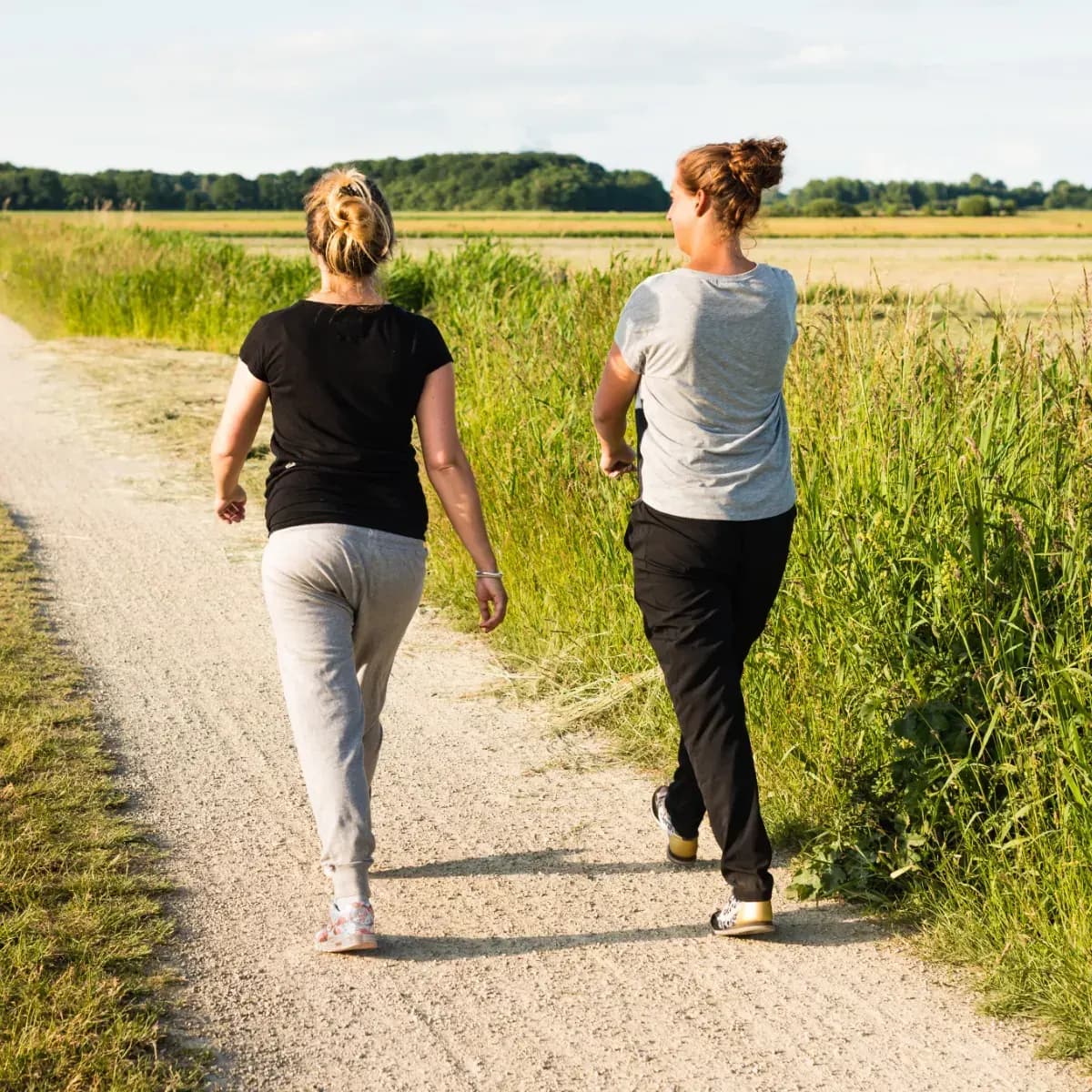 Two women walking a sunlit path, representing the journey of growth