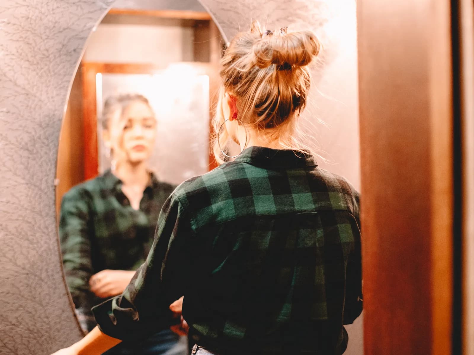 Woman studying her reflection in a hallway mirror