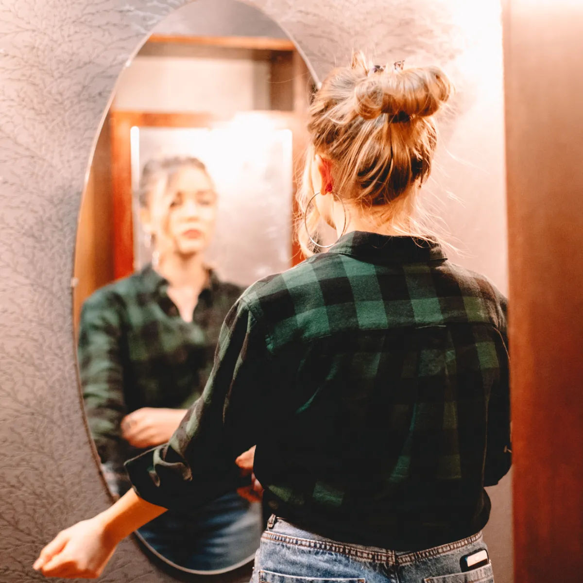 Woman gazing at her reflection in a hallway mirror