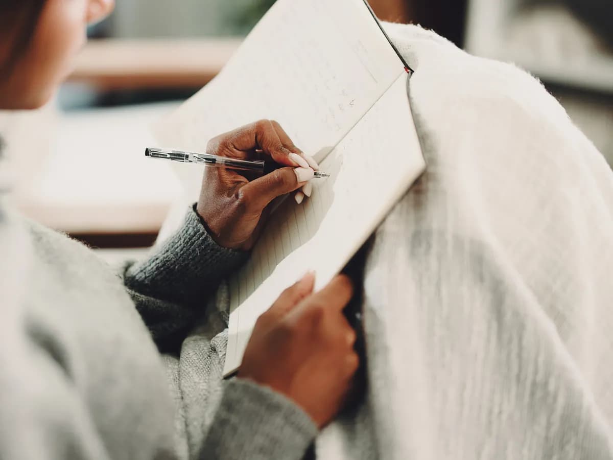 Woman journaling on a sofa, reflecting on thoughts and feelings