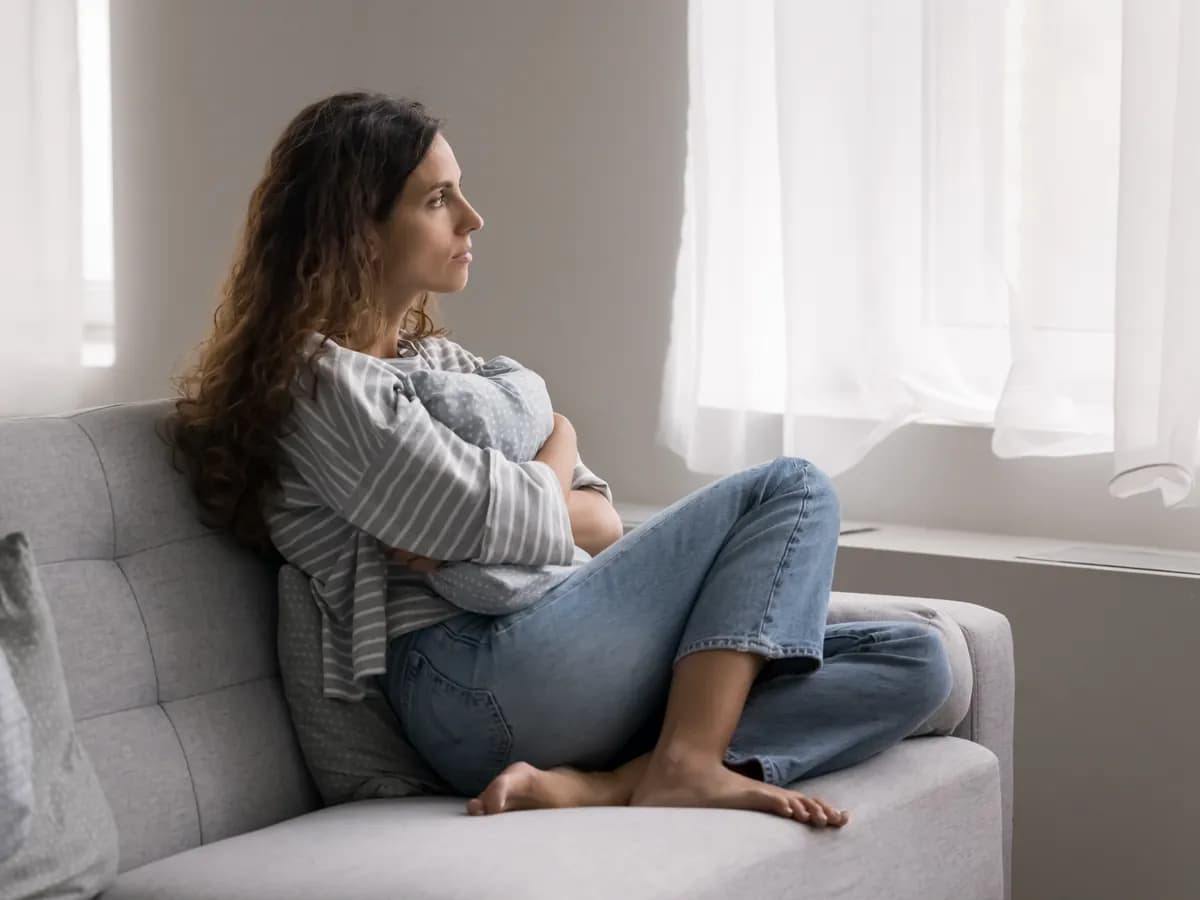 Pensive woman on a couch processing difficult thoughts